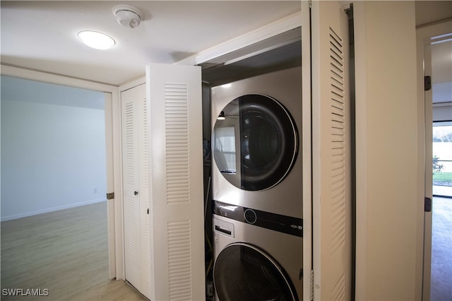 washroom featuring stacked washing maching and dryer and light hardwood / wood-style floors