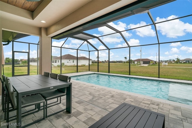 view of pool featuring a lawn, glass enclosure, and a patio