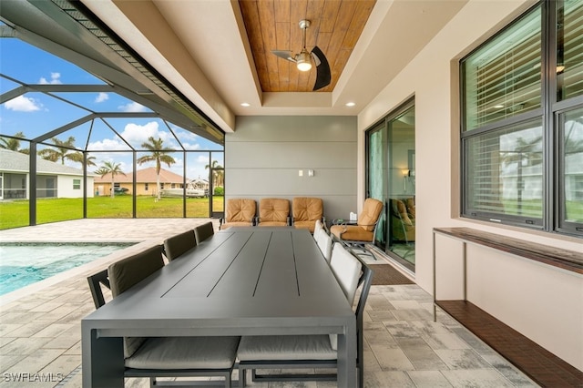 view of patio featuring glass enclosure, ceiling fan, and a swimming pool