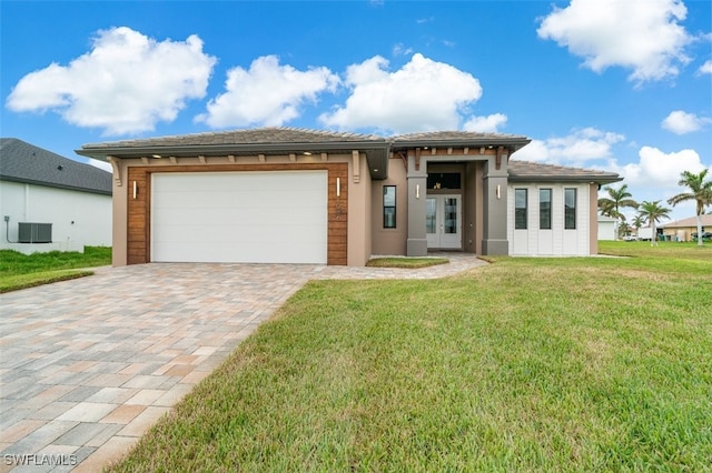 prairie-style house featuring a front yard, french doors, central AC, and a garage