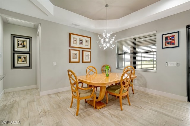 dining space featuring light wood-type flooring, a tray ceiling, and an inviting chandelier