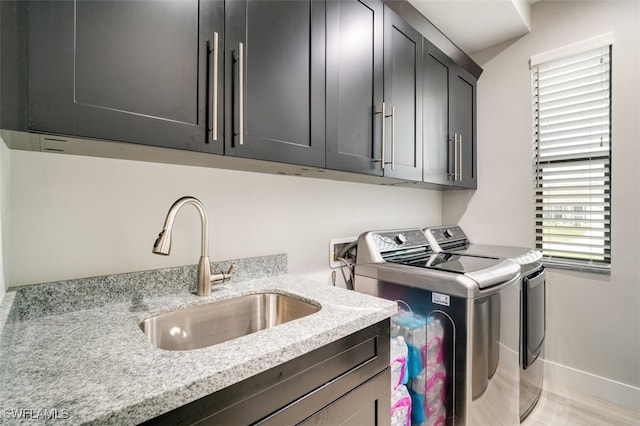 laundry area featuring cabinets, separate washer and dryer, and sink