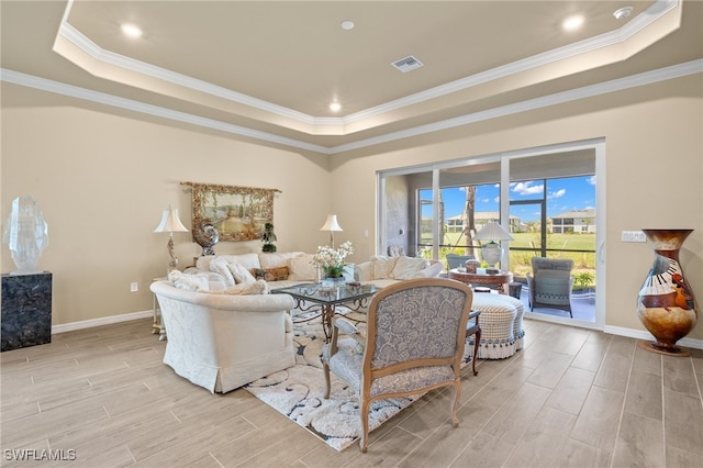 living room with ornamental molding, a raised ceiling, and light hardwood / wood-style floors