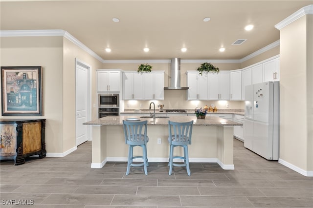 kitchen with white cabinetry, wall chimney exhaust hood, a kitchen island with sink, and stainless steel appliances