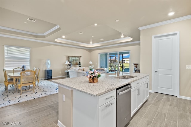 kitchen with white cabinetry, sink, stainless steel dishwasher, a tray ceiling, and a center island with sink