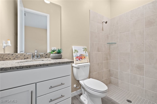 bathroom with vanity, hardwood / wood-style floors, toilet, and a tile shower