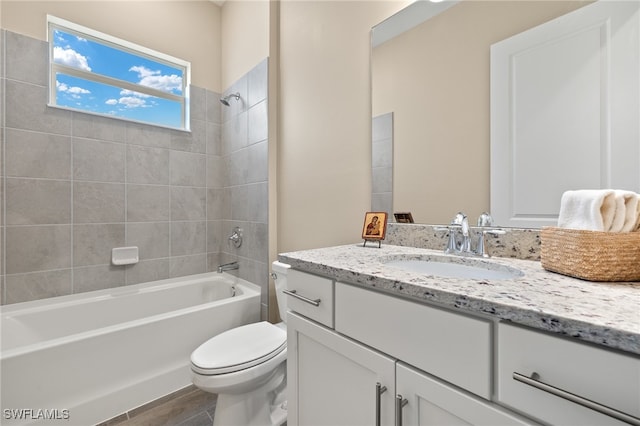 full bathroom featuring vanity, tiled shower / bath combo, hardwood / wood-style flooring, and toilet