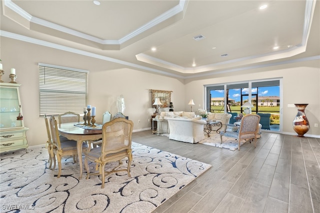 dining room featuring a raised ceiling, crown molding, and light wood-type flooring