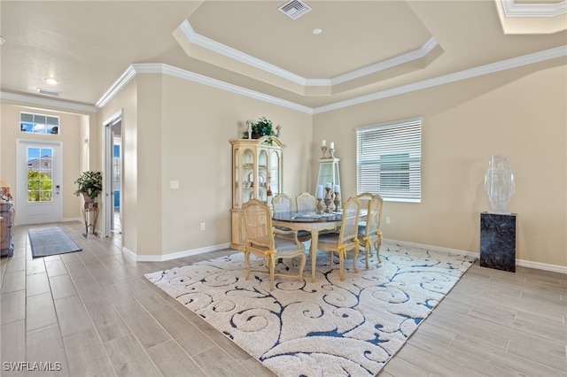 dining space with a tray ceiling, light hardwood / wood-style flooring, and ornamental molding