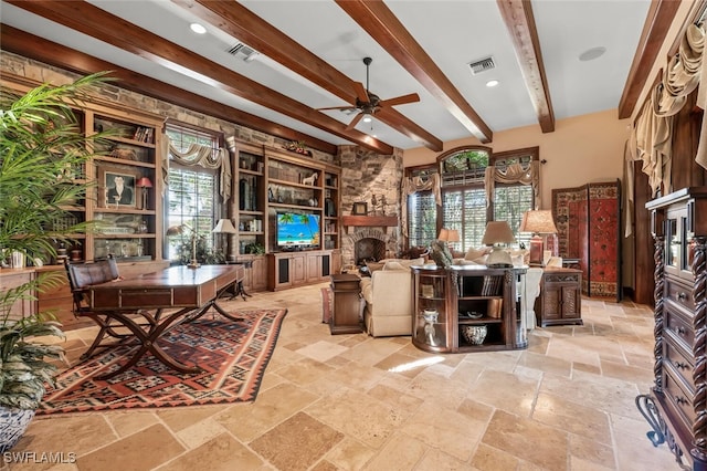 office area with a fireplace, beam ceiling, and ceiling fan