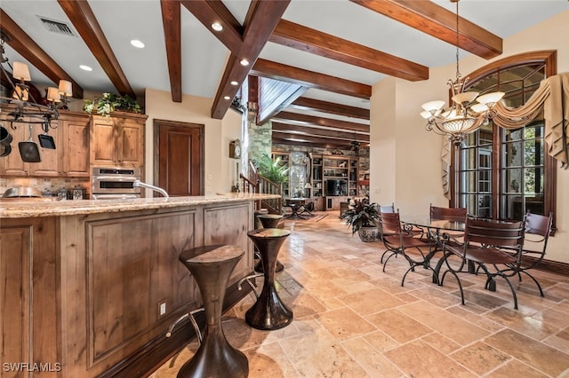 kitchen featuring light stone countertops, an inviting chandelier, oven, and beamed ceiling