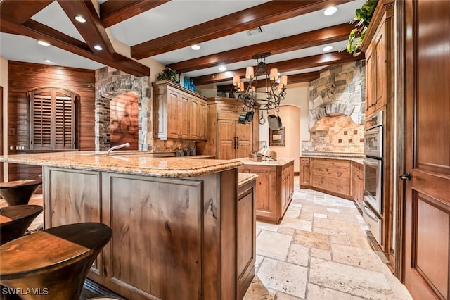 bar with light stone countertops, decorative light fixtures, a notable chandelier, beamed ceiling, and wood walls