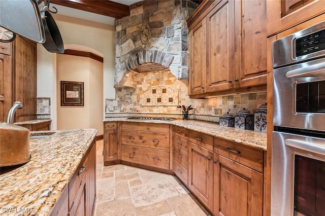 kitchen featuring decorative backsplash, light stone countertops, stainless steel appliances, sink, and beamed ceiling