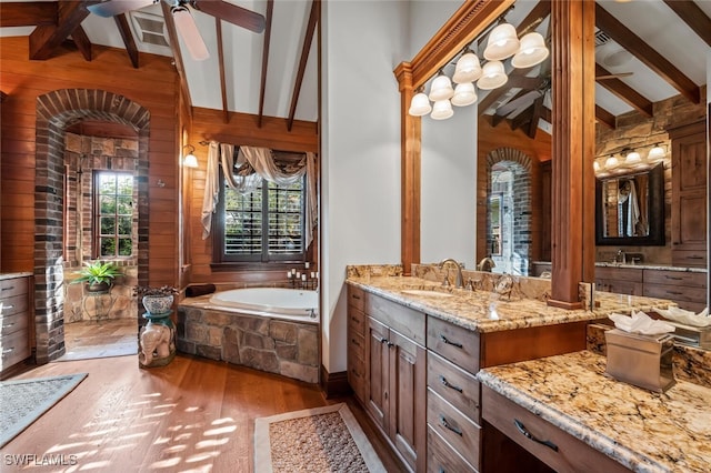 bathroom with a bathing tub, vaulted ceiling with beams, wood-type flooring, wooden walls, and vanity