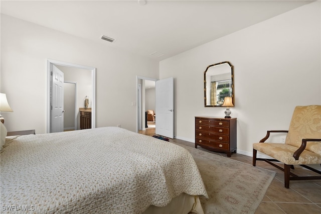 bedroom with connected bathroom and tile patterned flooring