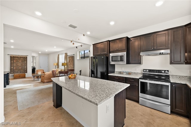 kitchen featuring dark brown cabinets, a center island, stainless steel appliances, and light stone counters