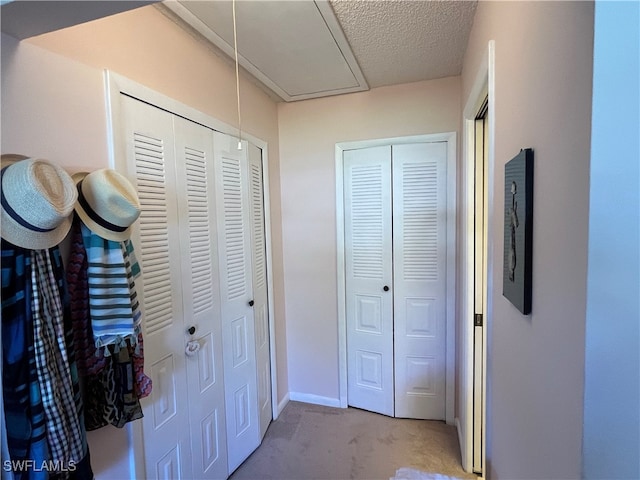 hallway with a textured ceiling and light colored carpet