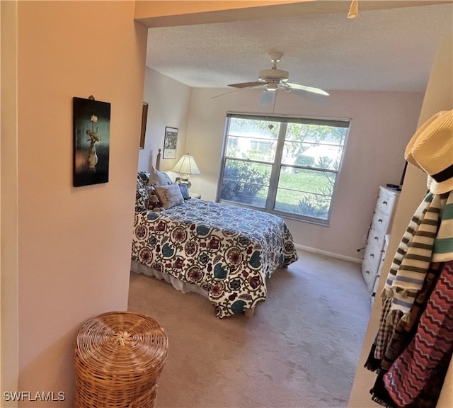 carpeted bedroom with ceiling fan and a textured ceiling