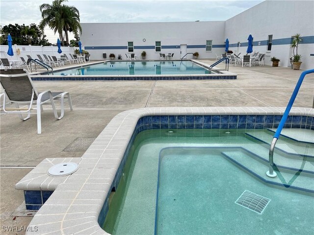 view of swimming pool with a patio area and a community hot tub