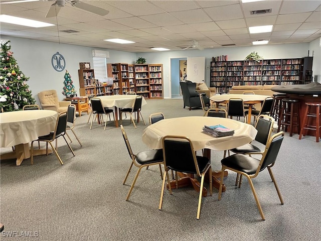 carpeted dining area featuring a drop ceiling and ceiling fan