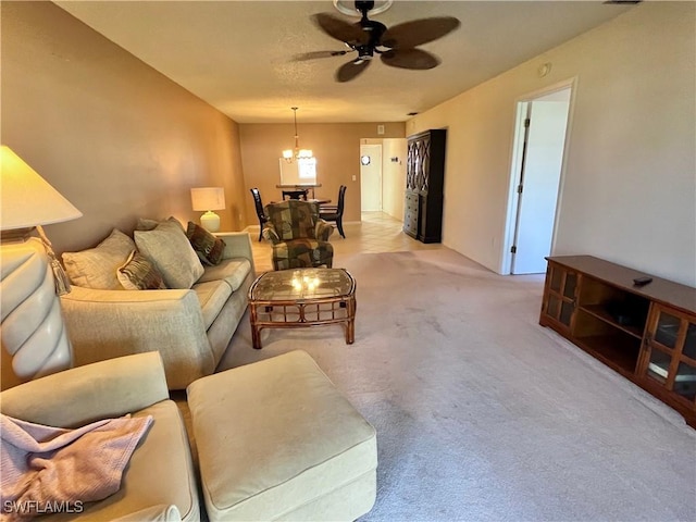 carpeted living room featuring ceiling fan with notable chandelier