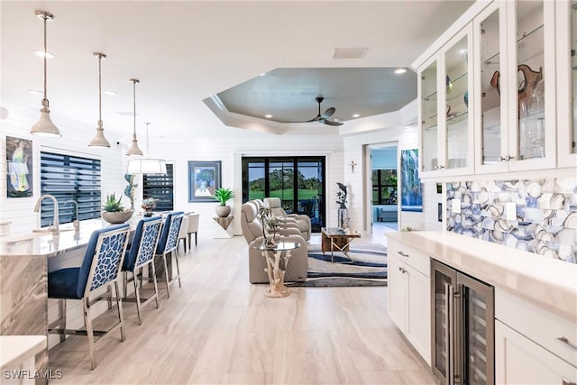 kitchen featuring a kitchen breakfast bar, white cabinetry, hanging light fixtures, and wine cooler