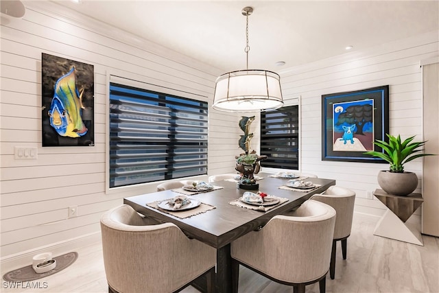 dining room featuring light hardwood / wood-style floors and wood walls