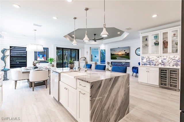 kitchen with white cabinets, decorative light fixtures, a kitchen island with sink, and dishwasher