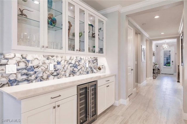 bar with white cabinetry, crown molding, and beverage cooler