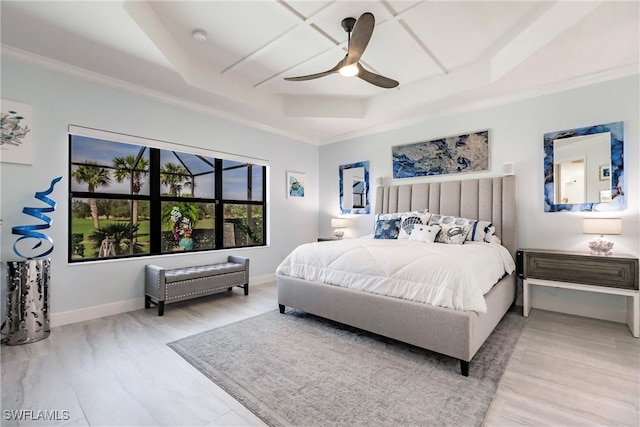 bedroom with hardwood / wood-style floors, ceiling fan, ornamental molding, and a tray ceiling