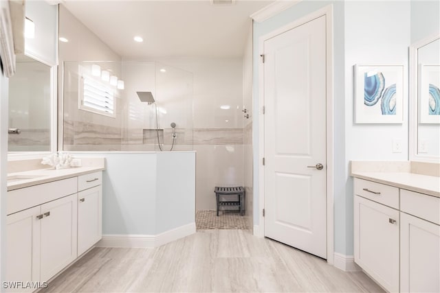 bathroom with hardwood / wood-style floors, vanity, and a tile shower