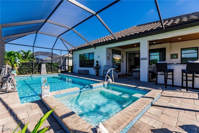 view of pool featuring exterior bar, a lanai, and a patio area