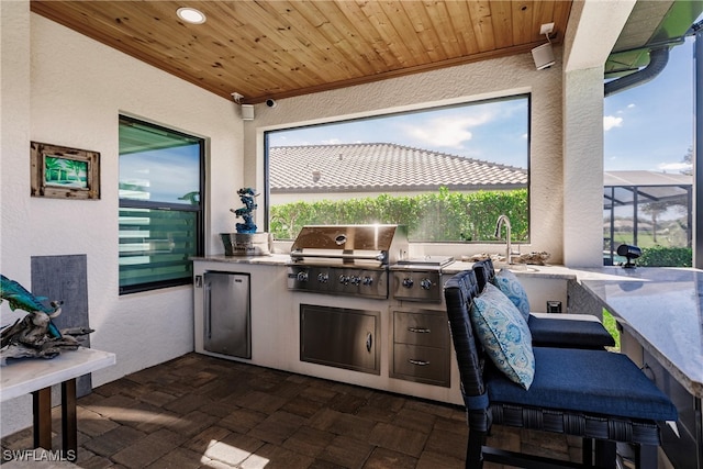 view of patio with a grill, sink, glass enclosure, and exterior kitchen