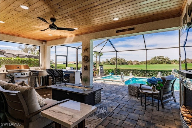 view of patio with a grill, an outdoor living space with a fire pit, an outdoor kitchen, and glass enclosure