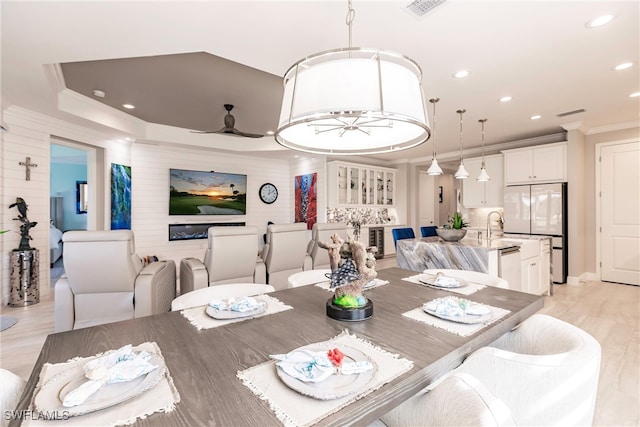 dining space with ceiling fan with notable chandelier, light wood-type flooring, and crown molding