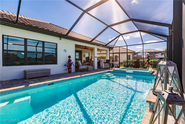 view of pool with outdoor lounge area, ceiling fan, glass enclosure, a patio area, and an in ground hot tub