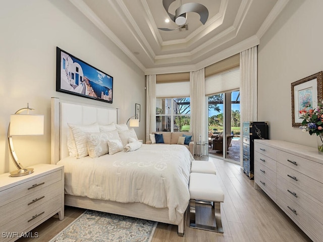 bedroom featuring a raised ceiling, access to exterior, light hardwood / wood-style floors, and ornamental molding