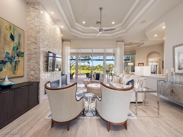 living room with a tray ceiling, ceiling fan, light hardwood / wood-style floors, and ornamental molding