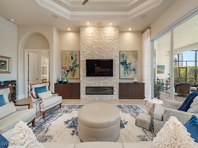 living room with crown molding, wood-type flooring, a fireplace, and a tray ceiling