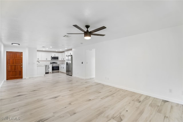 unfurnished living room with ceiling fan, sink, and light wood-type flooring