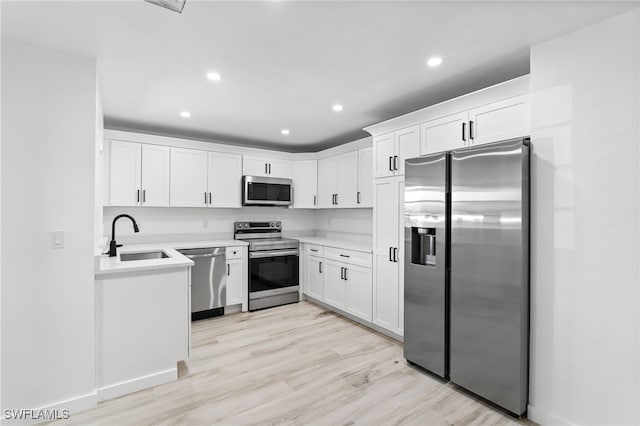 kitchen featuring white cabinets, stainless steel appliances, light hardwood / wood-style flooring, and sink