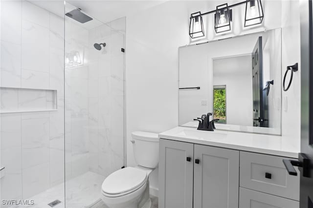 bathroom with a tile shower, vanity, and toilet