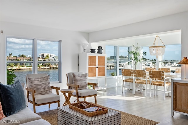 sitting room featuring hardwood / wood-style flooring, a water view, a wealth of natural light, and an inviting chandelier