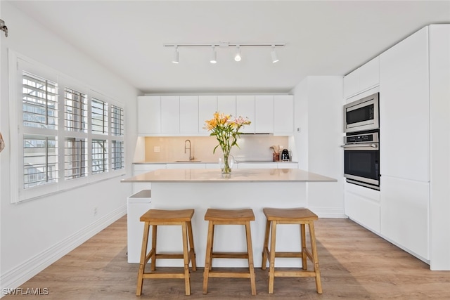 kitchen featuring a kitchen island, white cabinetry, appliances with stainless steel finishes, and light hardwood / wood-style flooring