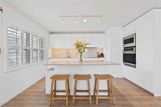 1100 8th Ave S Unit 230K, Naples, FL 34102 - kitchen with appliances with stainless steel finishes, track lighting, a breakfast bar, a center island, and light countertops