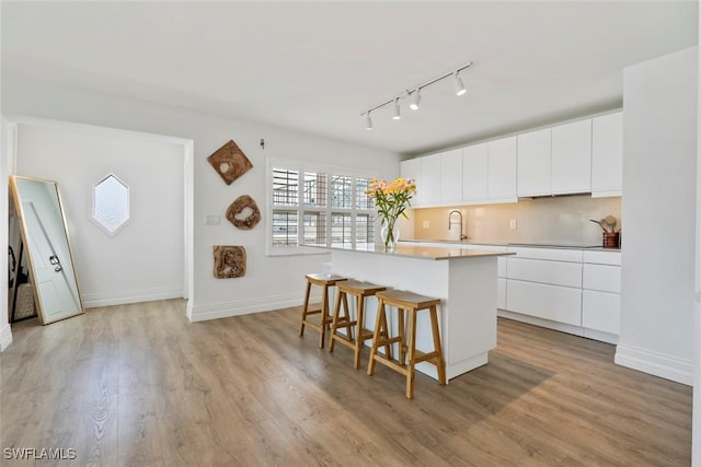 1100 8th Ave S Unit 230K, Naples, FL 34102 - kitchen featuring a kitchen bar, rail lighting, a kitchen island, a sink, and white cabinetry