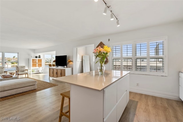 kitchen featuring light wood-type flooring, white cabinetry, a kitchen island, and plenty of natural light