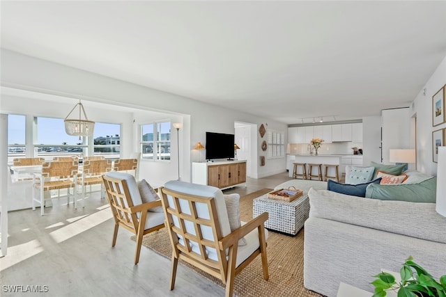 living room with light hardwood / wood-style floors and a notable chandelier