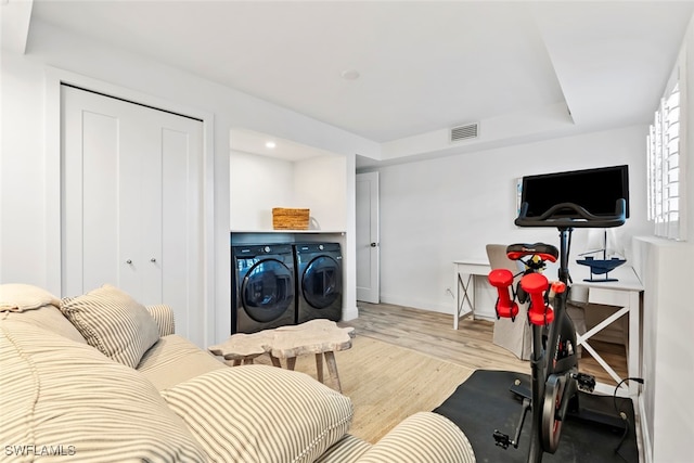 workout room with washer and dryer and light wood-type flooring