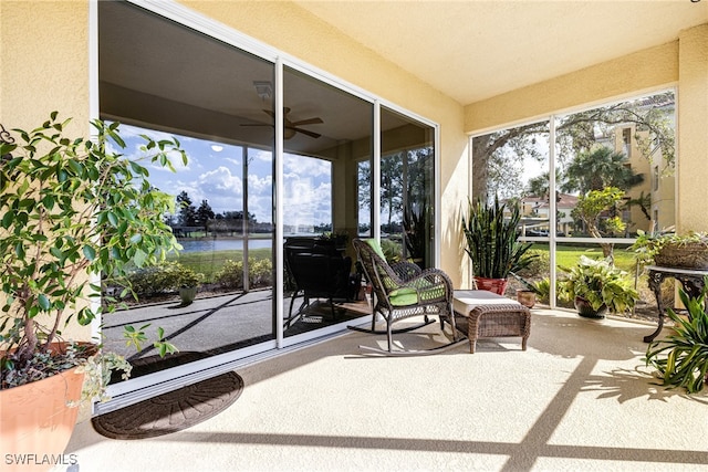 sunroom / solarium featuring ceiling fan, a water view, and a wealth of natural light